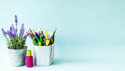 On a blue background on the table are school supplies and stationery, pencils, pens, scissors, felt-tip pens.  Copy space for text, front view.  Back to school concept.  Online learning.