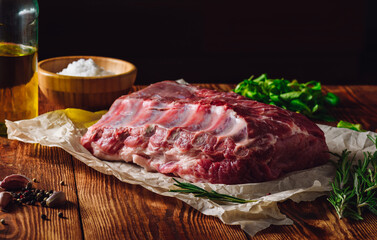 Raw Pork Ribs on Parchment with Greens and Spices.