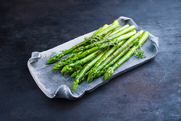 Green asparagus glazed with cress as garnish served as close-up on a design tray with text space