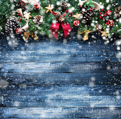 Merry Christmas Frame with Snow and real wood green pine, colorful baubles, knots with berries and other seasonal stuff over an old wooden aged background