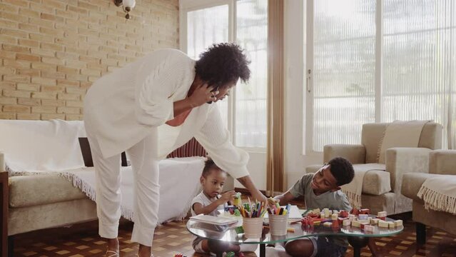 muher Brasileira falando no celular enquanto ajuda seu filho com a licao de casa na sala no Braslil