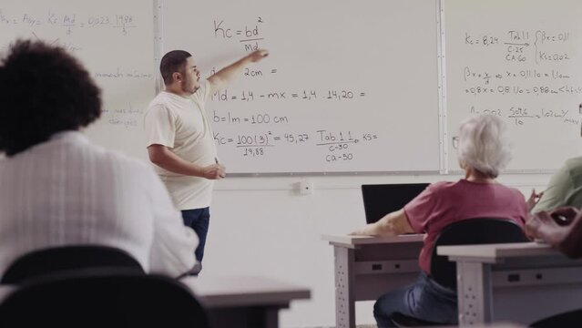 professor Brasileiro explicando um problema de matem&aacute;tica na lousa durante aula em um curso para adultos no Brasil
