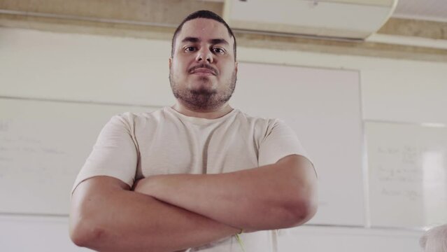 sorrindo de bra&ccedil;os cruzados na sala de aula em um curso para adultos no Brasil