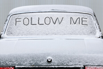 Covered with snow car with the inscription on the rear window