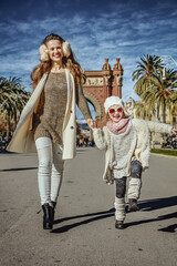 in Barcelona for a perfect winter. Full length portrait of happy trendy mother and daughter near Arc de Triomf in Barcelona, Spain walking