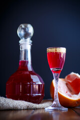 sweet grapefruit alcoholic cordial in the decanter with a glass on a dark table