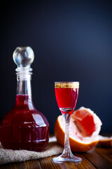 sweet grapefruit alcoholic cordial in the decanter with a glass on a dark table