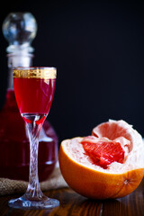 sweet grapefruit alcoholic cordial in the decanter with a glass on a dark table