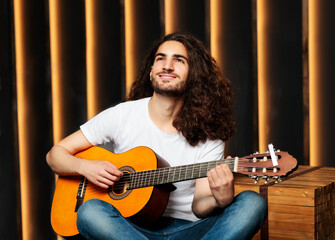 Obraz premium Cheerful Arabic Young Guy Playing Acoustic Guitar In Black Studio