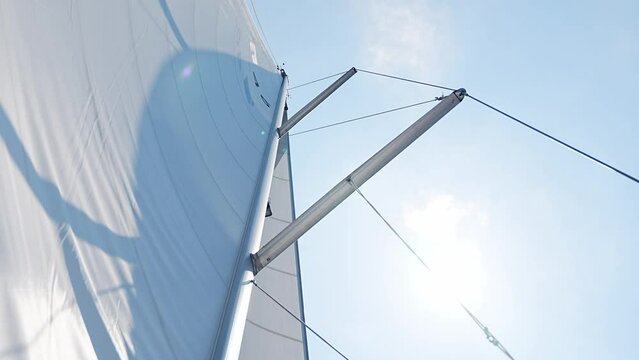 Yacht sailing in an open sea. Close-up view of sails of a sailing yacht in the wind and clear sky with sun