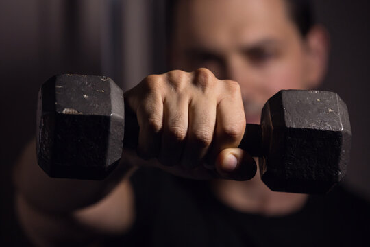 Young Man Holding Up Weight Towards Camera In The Gym