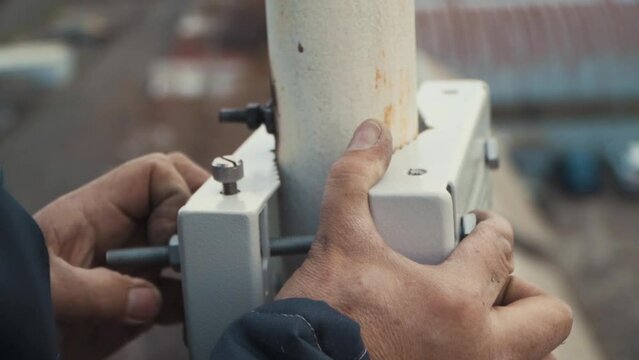 Mounting the attachment on the telecommunication pole. Close-up. The hands of a worker. Engineer. At a height.