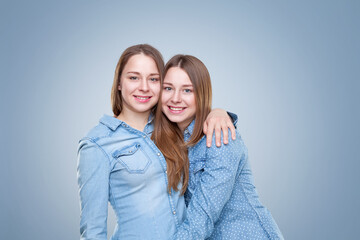 Studio portait of young and happy twin sisters embracing