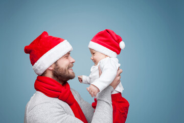 Father with his baby boy wearing Santa hats celebrating Christmas
