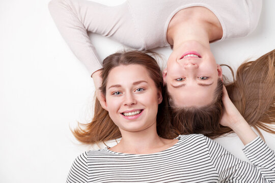 Portrait of young and happy sisters lying on the floor