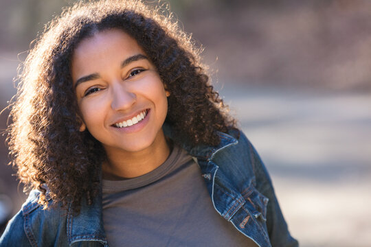 Outdoor portrait of beautiful happy mixed race African American girl teenager female young woman smiling laughing with perfect teeth