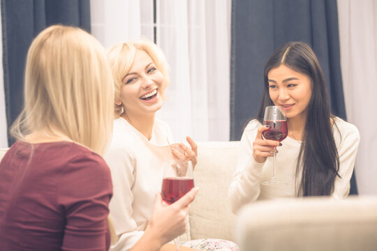 Toned picture of cheerful friends businesswomen having party at home. Beautiful ladies smiling and communicating about every day life: work, home, men.