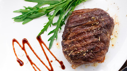 Medium grilled beefsteak on a plate with cherry tomato and arugula