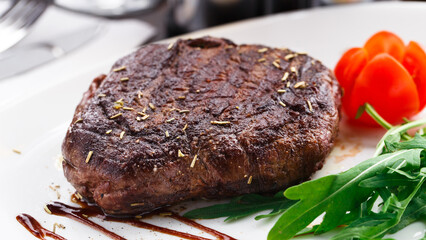 Medium grilled beefsteak on a plate with cherry tomato and arugula