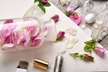  perfume empty bottle around roses and petals settled at authentic provence background. Perfumer, beauty and trendy concept.  flat lay
