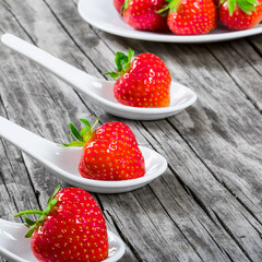 strawberries on a porcelain spoons on an old rustic table