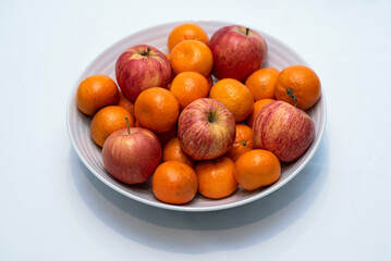 apples and oranges in white bowl