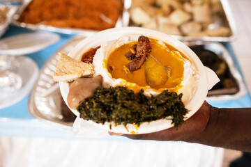 foreground of traditional western cameroon food, taro with yellow sauce served at the table,...