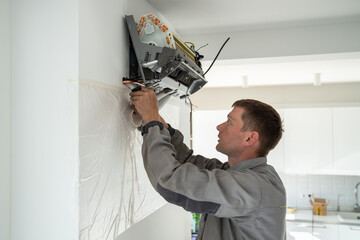Man technician worker in uniform fixing repairing apartment air conditioner, installing...