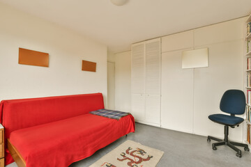 a living room with a red couch and bookshels on the wall behind it is a bookcase that has been used...