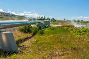 Geothermal plant pipes and a steaming river, Iceland