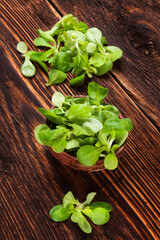 Fresh lamb's lettuce salad in wooden bowl on old wooden vintage background. Fresh salad, rustic vintage country style image.