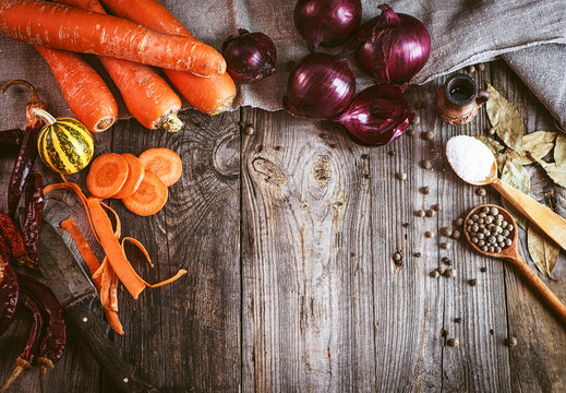 Fresh raw vegetables and spices on gray wooden surface, empty space in the middle, vintage toning