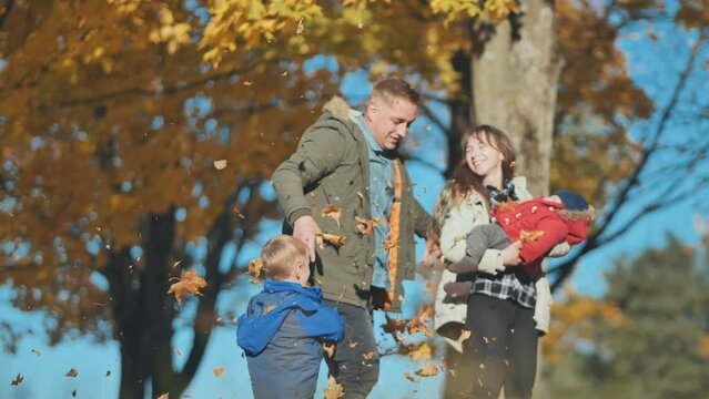 A young, happy family in the park sprinkled with leaves.