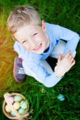 cheerful little boy enjoying easter egg hunt at spring