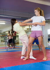 Two girls learn to do a painful hand grip in a self-defense lesson