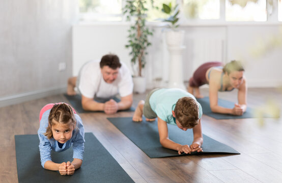 Parents together with children in yoga pose upward-facing dog at gym