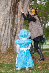 Little girl on grandma costume playing with her mom. Real family having fun while using costumes of the Little red riding hood tale in Halloween.