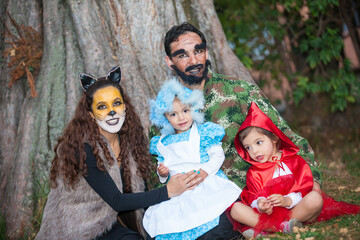 Real family having fun while using costumes of the Little red riding hood tale in Halloween.