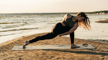 Favorite workout yoga asana outdoors at sunset, a woman trains a flexible body. Uses a non-slippery mat material.