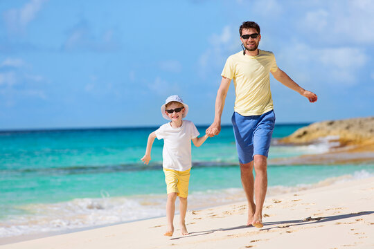 happy family of two, father and son, running and enjoying summer vacation together at perfect caribbean beach