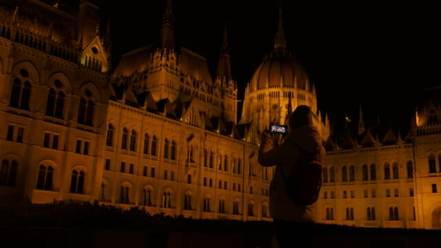 Souvenir photos of budapest parliament. A tourist woman takes a photo for souvenir by the Budapest goverment building in the night.