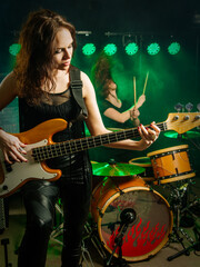 Fototapeta na wymiar Photo of a female bass player and drummer of a rock band playing on stage.