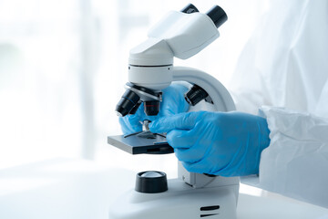 Doctor hand taking a blood sample tube from a rack with machines of analysis in the lab background,...