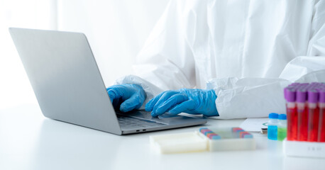 Doctor hand taking a blood sample tube from a rack with machines of analysis in the lab background, Technician holding blood tube test in the research laboratory.