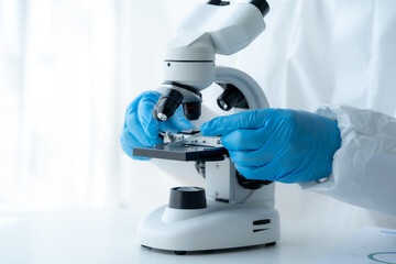 Doctor hand taking a blood sample tube from a rack with machines of analysis in the lab background,...
