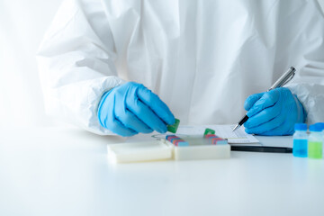 Doctor hand taking a blood sample tube from a rack with machines of analysis in the lab background, Technician holding blood tube test in the research laboratory.