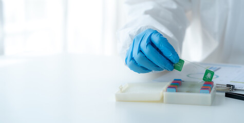 Doctor hand taking a blood sample tube from a rack with machines of analysis in the lab background, Technician holding blood tube test in the research laboratory.