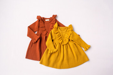 Dresses for a girl. Yellow and orange dresses. Children's wardrobe, children's clothing. White background, top view. High quality photo
