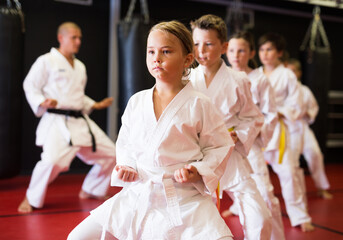 Fototapeta na wymiar Preteen girl wearing in kimono attempting to master new moves in sport gym
