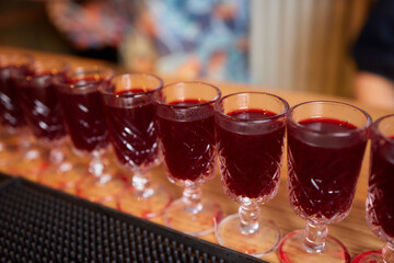 cocktails shots are on a tray on the bar counter. red cocktail shots on the bar.